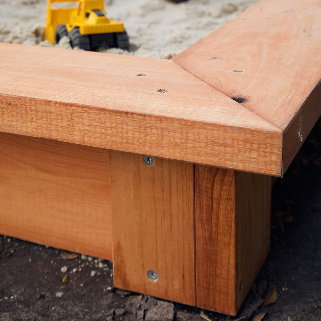 Corner detail of timber raised sandpit with toy truck in the background
