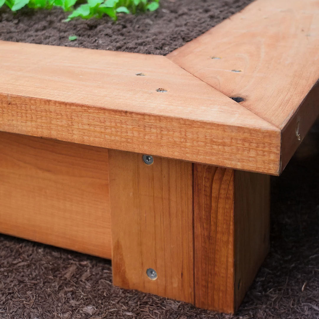Close-up of a wooden raised garden bed with soil in the background