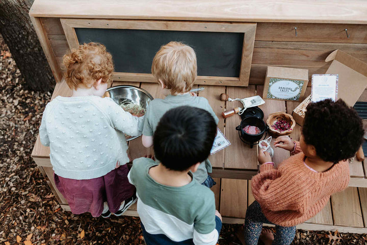 Kids playing Sensory Play at their Wooden Mud Kitchen creating potions