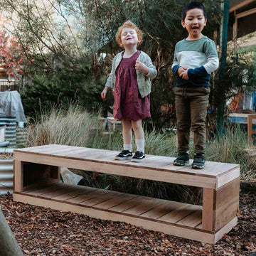 kids standing on a wooden bench