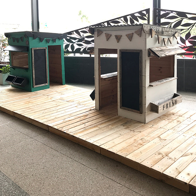 Two painted cubby houses sit on wooden decking panels