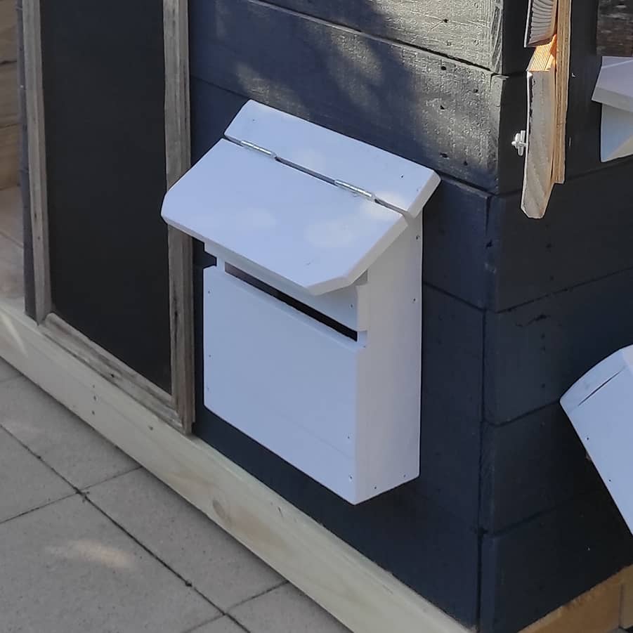 A painted toy letterbox on a wooden cubby house