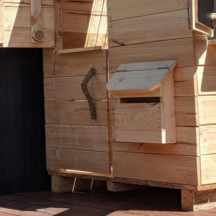 A wooden toy letterbox on an outdoor cubby house