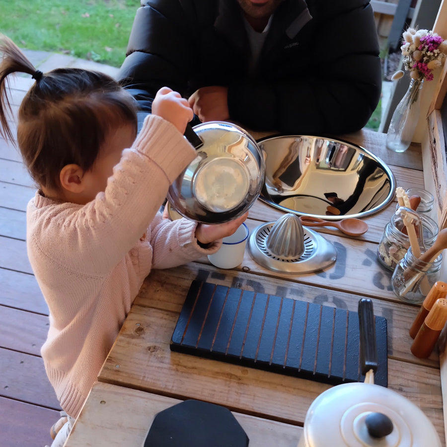 Little girl and her dad pretend play at a kids wooden play kitchen